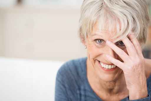 lächelnde seniorin fasst sich an den kopf lächelnde seniorin fasst sich an den kopf